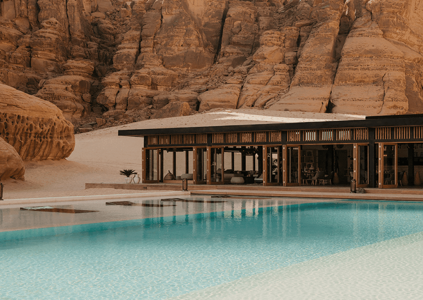 Piscina y pabellón de una propiedad entre acantilados del desierto, a pleno día